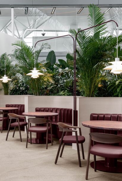 Oxblood-coloured booth seating with lush planting behind