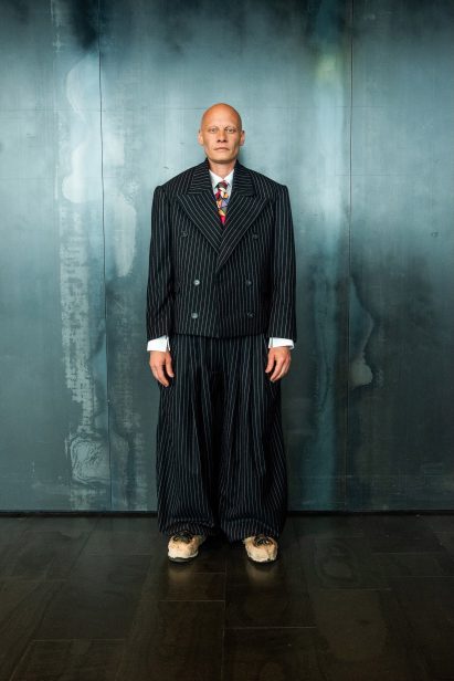 a photograph of a person wearing a black and white pinstripe suit