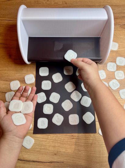 a person's hands holding white square tokens