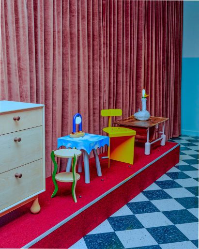 Avant-garde designs presented on a red plinth against a velvet curtain