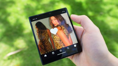 Photo of a person's hand holding the square and compact iKKO MindOne phone while they look at an image of a woman with a small white heart in the middle