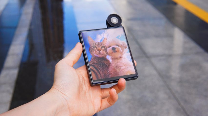 Photo of a person's hand as they hold the iKKO MindOne phone and look at a picture of a dog and cat