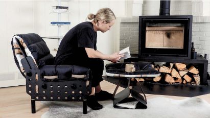 a photograph of a person reading next to a fireplace