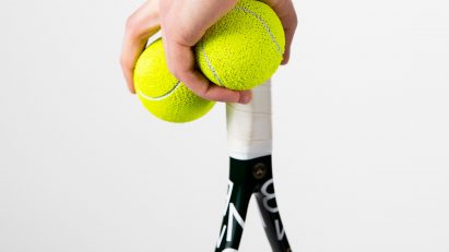 Hand holding tennis balls and tennis racket