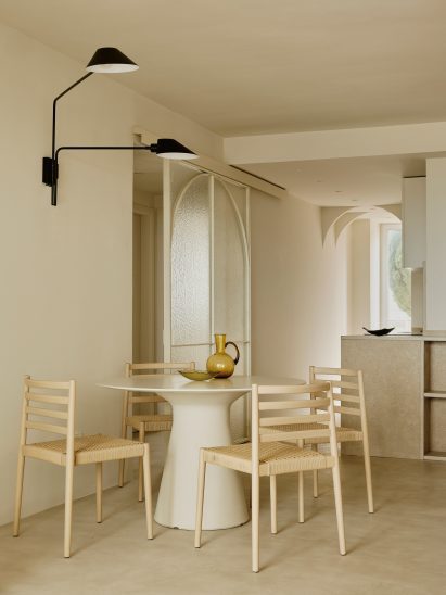 Dining area with wooden chairs and black wall lamp above