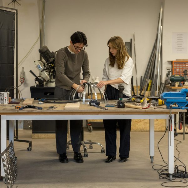 Two people in a workshop working on a metal structure