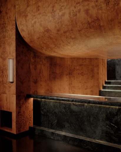 Dark green stone bar with burl wood veneer panelling above and around