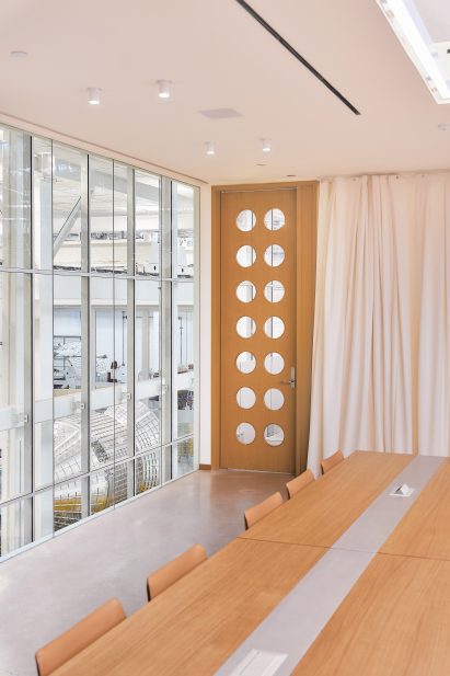 Photo of a mezzanine meeting room at Vast's Long Beach headquarters showing a view onto the fabrication floor through floor-to-ceiling windows