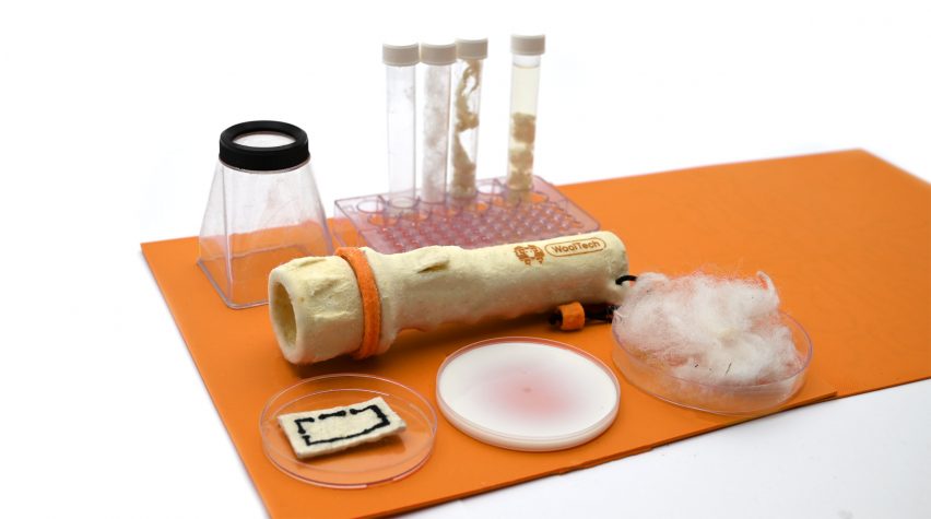Photo of the WoolTech torch laid on an orange mat and surrounded by material samples in test tubes and petri dishes