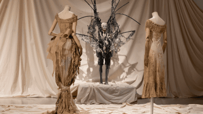 Three mannequins wearing shredded clothing on display