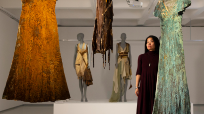 Woman looking at dirt-covered dresses hanging in gallery space