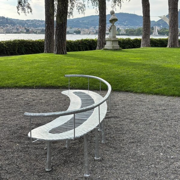 Steel bench on gravel in front of lawn with lake in background