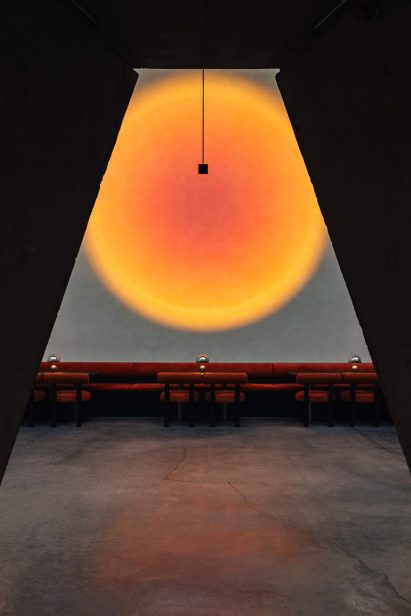 A warm glowing disk projected onto a wall above banquette seating