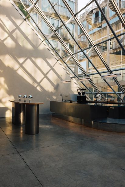 Bar counter and high-top table under an angled glass facade