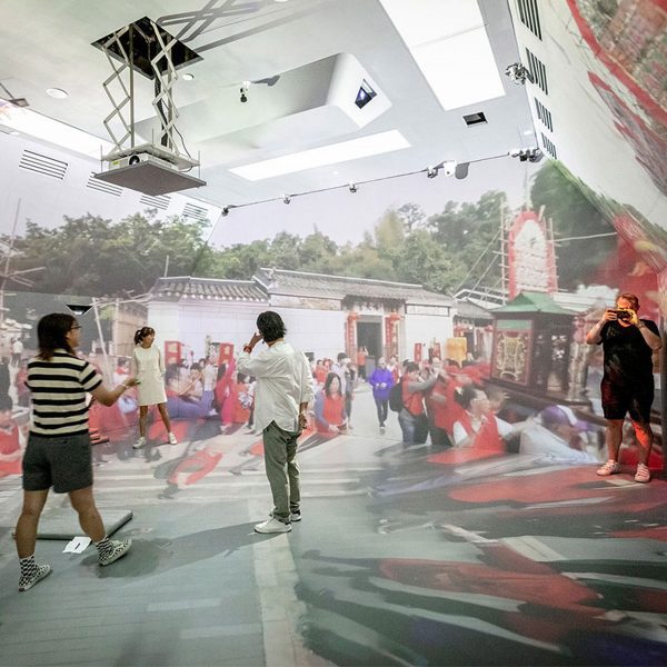 people standing in a room with projections on the walls