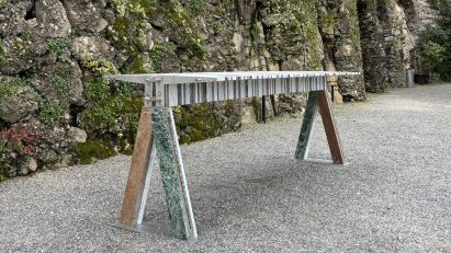 Table made from marble fragments and stainless steel brackets on an outdoor gravel area