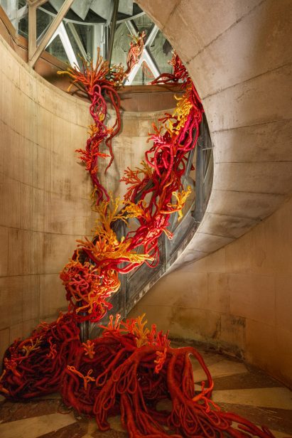 Hand-woven coral forms spilling down a spiral staircase