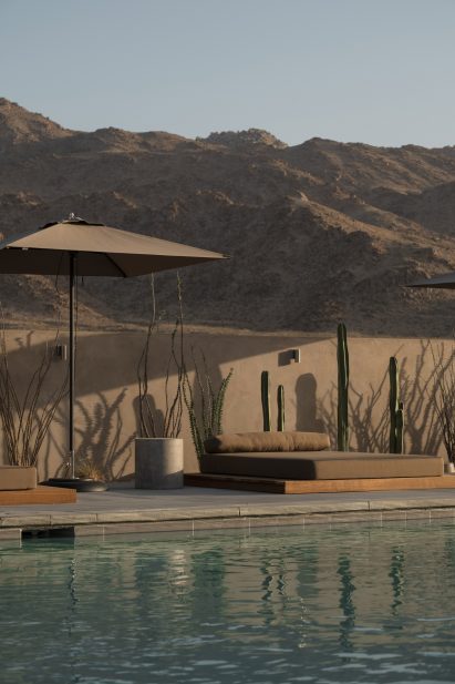 Swimming pool with low lounger, parasol, and mountains behind