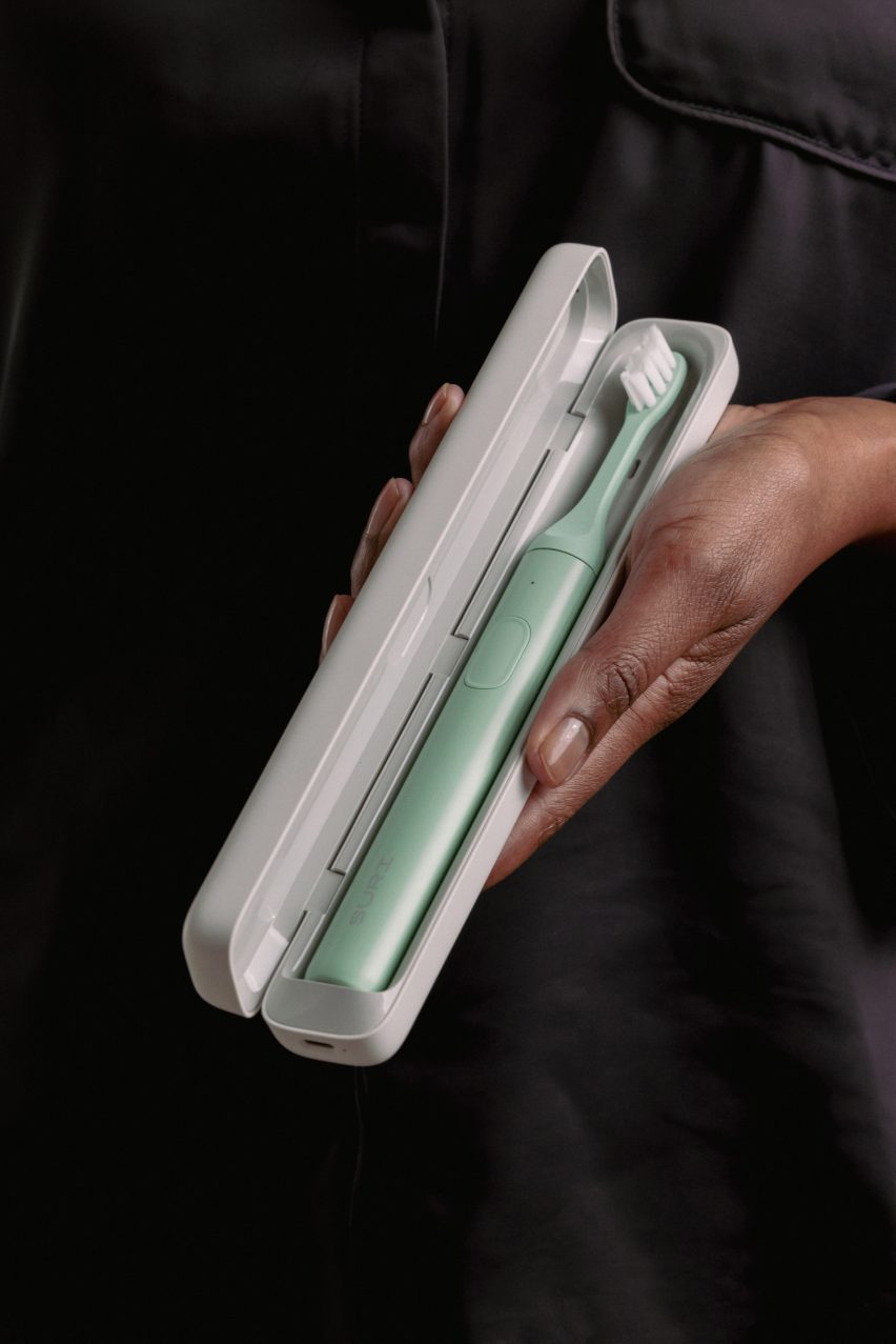 Photo of a mint green Suri 2.0 toothbrush in its travel case, a white rounded rectangular object