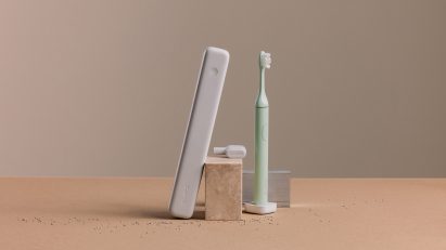 Photo of the Winter Fern coloured Suri 2.0 toothbrush in a studio setting alongside its case and a travel cover