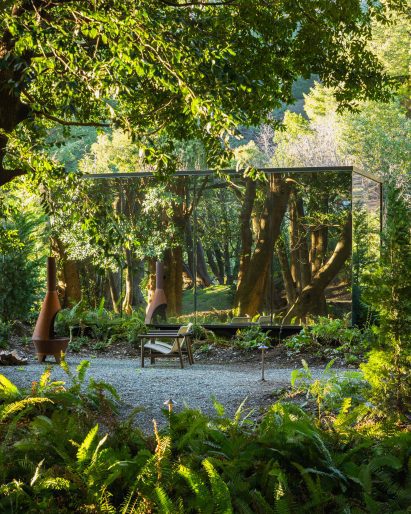 A mirrored cabin surrounded by lush greenery