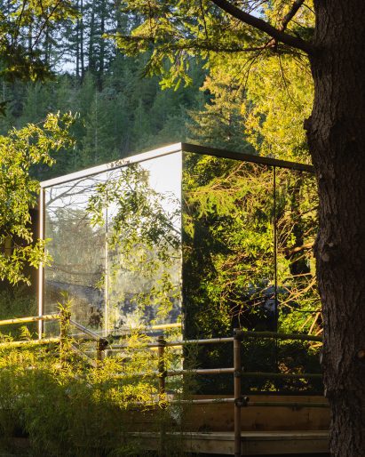 Corner of a mirrored cabin surrounded by trees