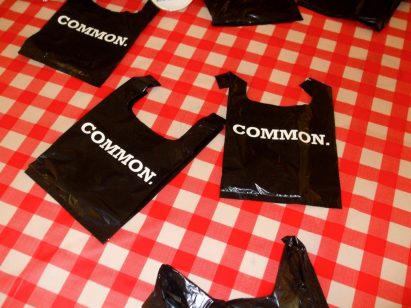 a photograph of black plastic bags with white text on them place on a red and white checkered table cloth