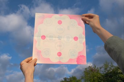 a photograph of a person holding up a poster in tones of pink and white