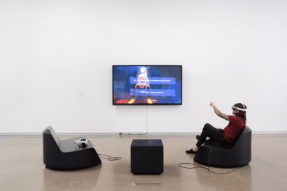 Two seats in front of a television screen mounted onto a wall