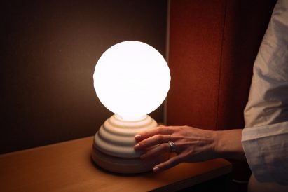 Hand touching the base of a bedside table lamp