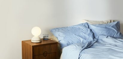 Bed with blue sheets and bedside table with spherical lamp