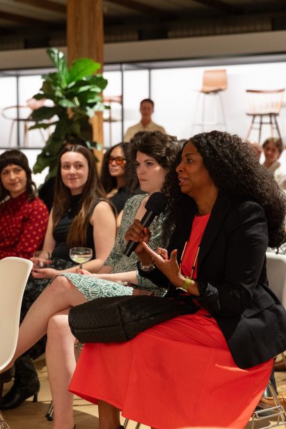 Speaker at the event in red dress and black jacket