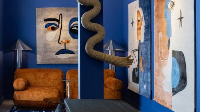 Photo of a living space with blue walls and rust-coloured art and sofa
