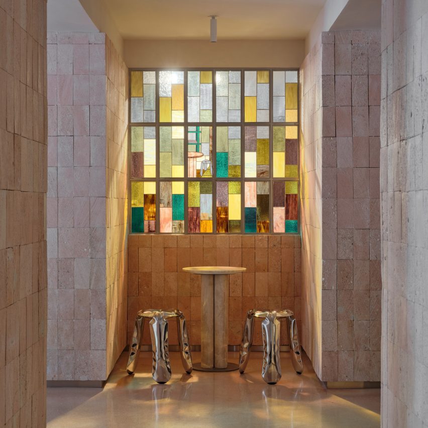 Photo of stools and a table by a stain glass window