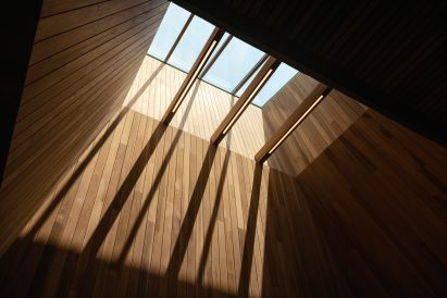 View up to a skylight at the top of a wood-wrapped opening