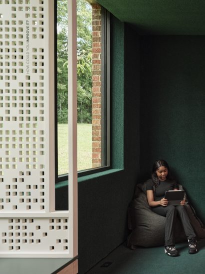Corner of a green room with a girl sat on a beanbag below a window