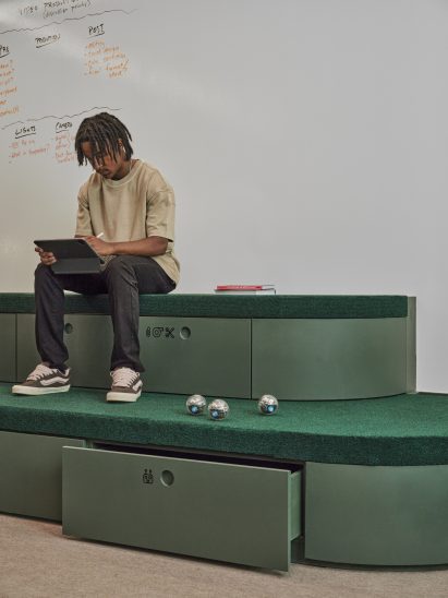 Boy using a tablet while sat on green bleachers