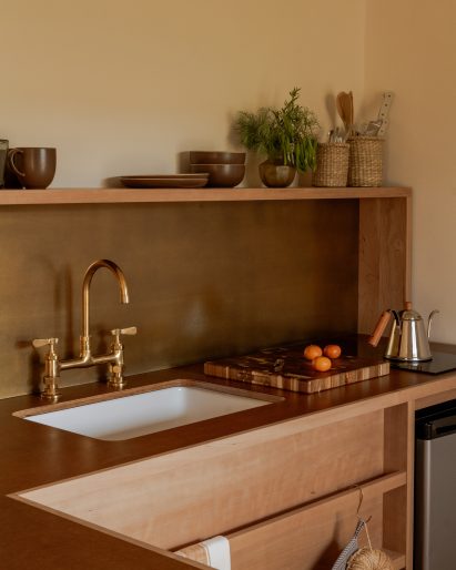 Kitchenette with wood cabinets and a brass backsplash