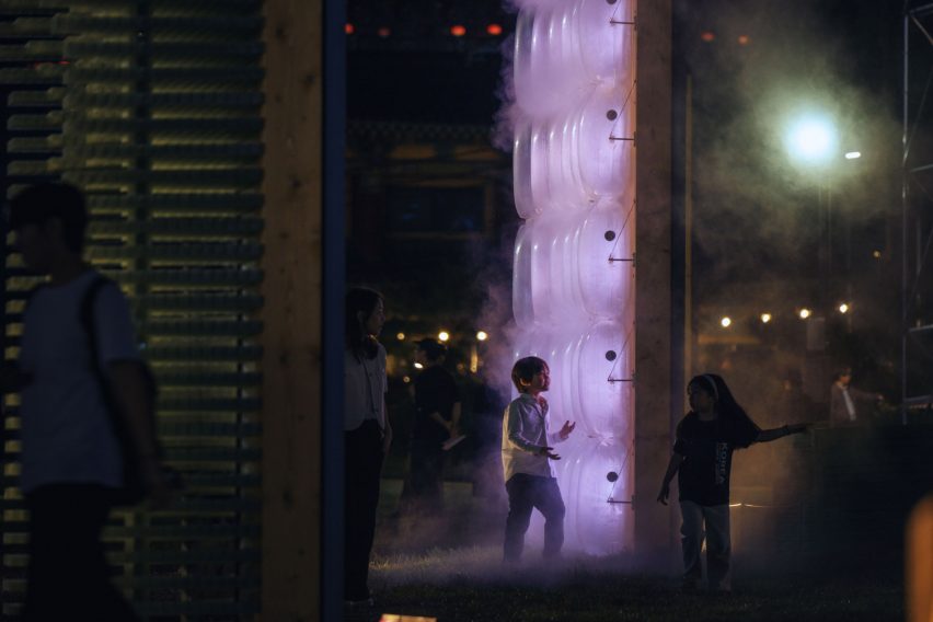 Kids playing by illuminated artwork