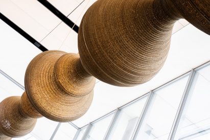 Low-angle view of suspended light sculpture under a glass roof