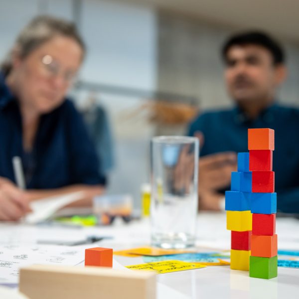 a photograph of coloured building blocks on a table with people in the background