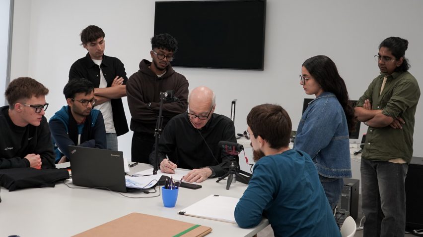 a photograph of students and a tutor sat at a desk