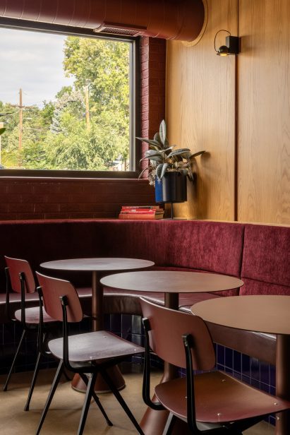 Corner banquette with oxblood red upholstery and modernist tables