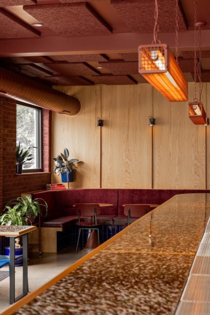 Bar with wood and brick walls, and oxblood-coloured ceiling and seating