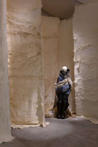 Photo of an elaborate navy-coloured wool garment by Sybrand Jansen on a mannequin in an exhibition