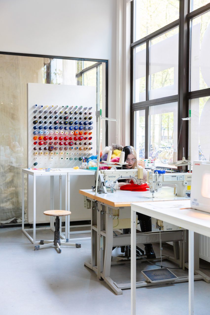 Photo of a person at work in a sewing station within an exhibition space at the New Order of Fashion LAB