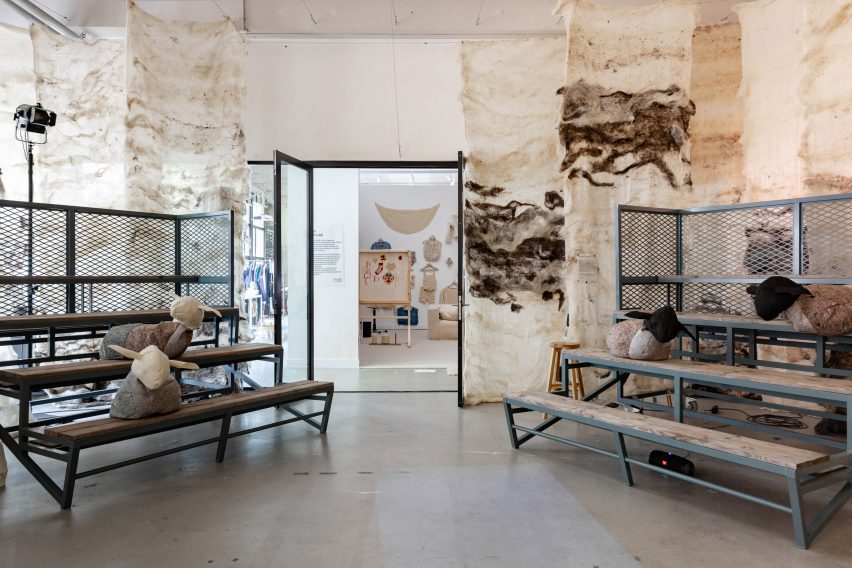 Photo of a room set up for talks within an exhibition featuring tiered bench seating with abstract stuffed sheep scattered on the seats