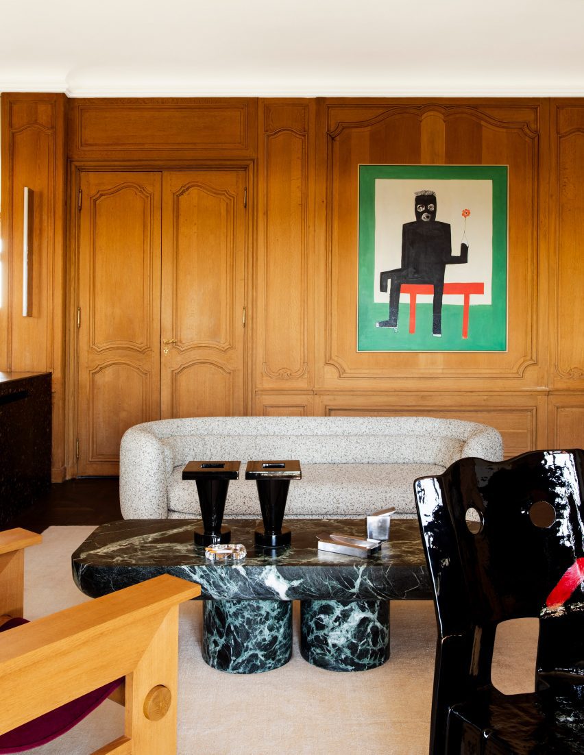 Photograph of the living room, showing a white sofa and a large black table with a white marbling effect.