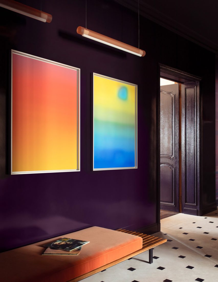 Photograph of a deep purple hallway with two colourful artworks on the wall.