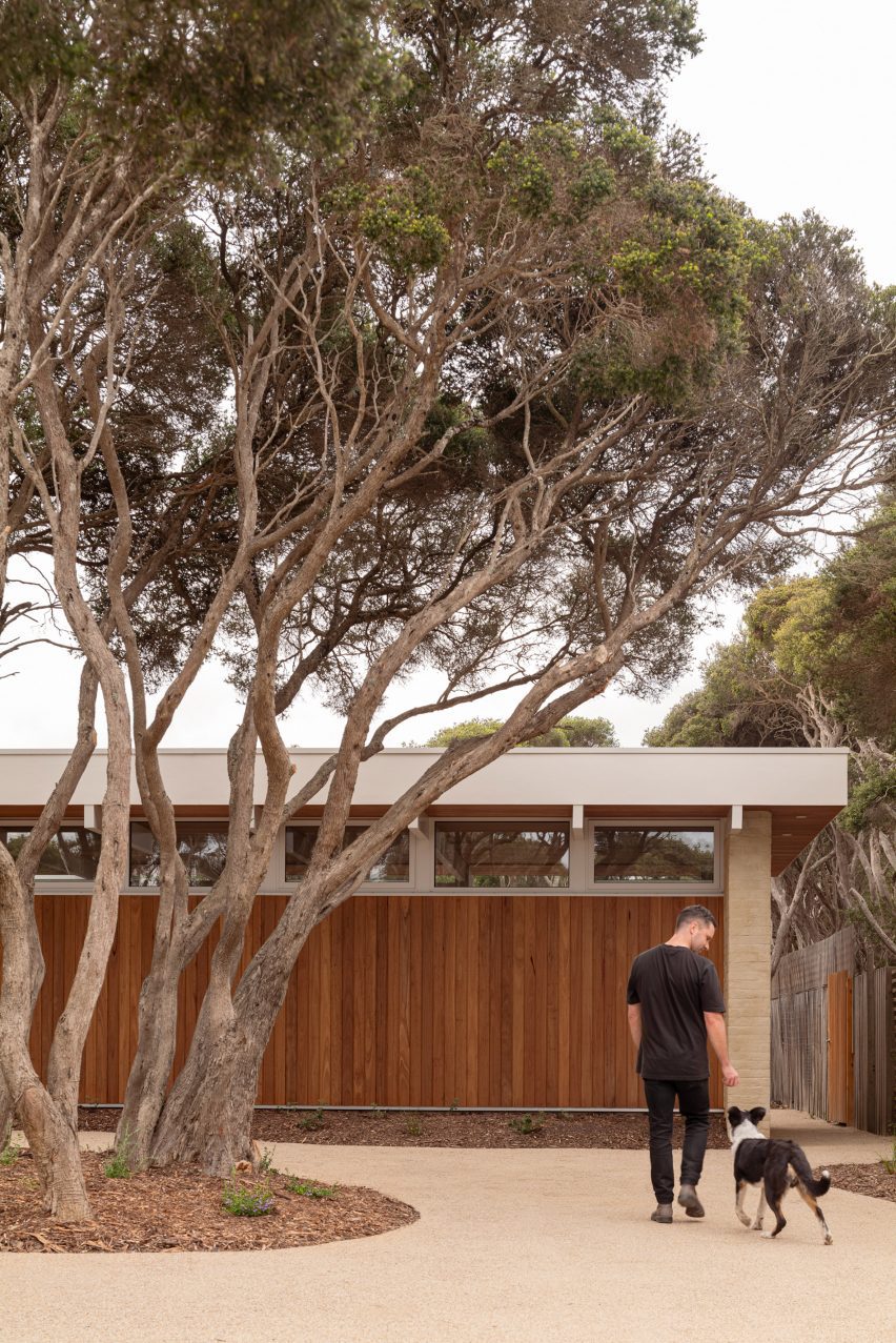 Person with dog outside single-storey house Australia